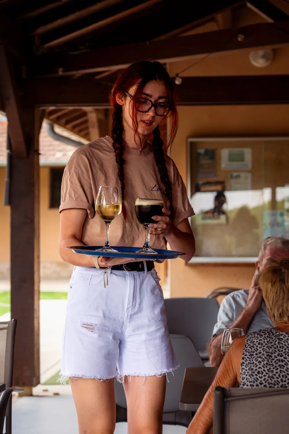 Serveuse apportant un plateau de boissons en terrasse