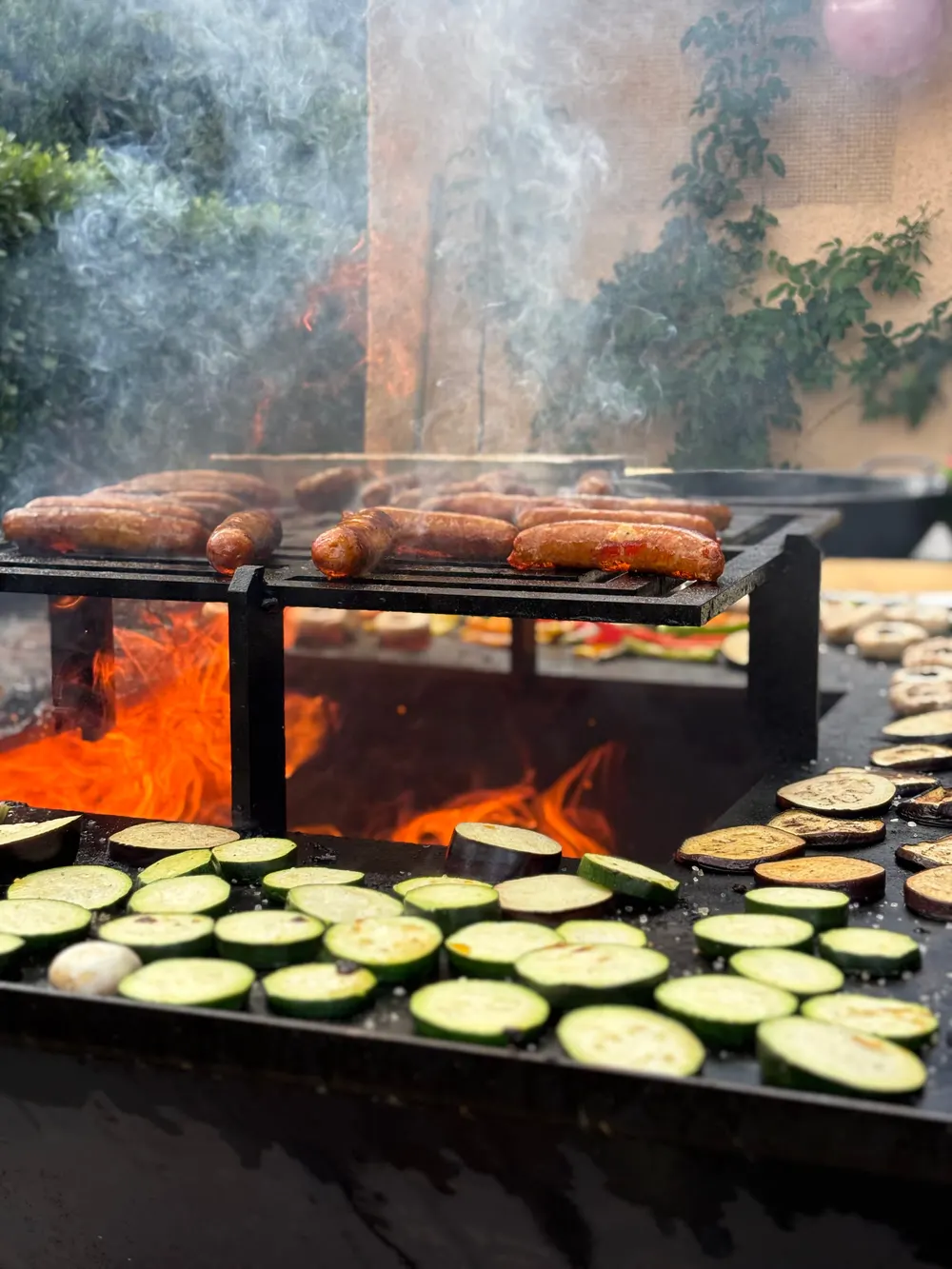 Saucisses et courgettes grillées au-dessus des flammes du braséro
